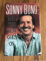 Front cover of the hardcover book 'And The Beat Goes On' showing a smiling Sonny Bono in a blue shirt.