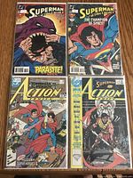 Four Superman comics laid out on wood, featuring Parasite, Champion of Space, Superman vs Superboy, and an Annual issue.