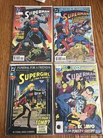 Four Superman comic books laid out on a wooden surface, showing their colorful covers and artwork.