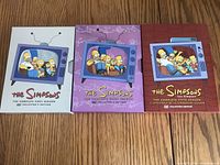 Photo of three DVD collectible box sets of The Simpsons seasons 4, 5, and 6 showing illustrated covers with the family on TV screens.