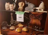 Shelf display of assorted animal figurines including owls, elephant, bird, turtles, metal owl sculpture highlighting variety of materials and forms