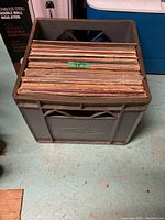 Image showing a gray plastic crate filled with about 34 children's vinyl records in their sleeve covers.