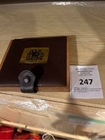 Closed view of brown leather box with gold Canada emblem and snap closure.