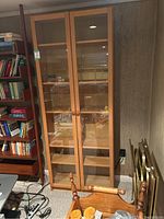 Front view of closed wooden bookcase with glass doors showing the frame, doors, and knobs.