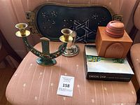 Photo of assorted Judaica items including candelabra, candlesticks, black tray with Star of David, wooden dreidel container, wooden box, books on Jewish cooking.