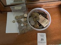 Overview of the coin lot showing a plastic container filled with mixed coins, a plastic bag labeled 'France' with coins inside, and a small folded foreign paper currency.