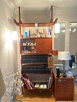 Full front view of MCM wood floating shelf unit showing five shelves, enclosed cabinet, integrated pendant lights and wood finish