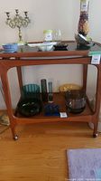 Front view of two-tier wooden serving cart with black top and casters