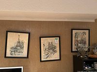 Three framed original watercolor paintings on wall depicting Paris landmarks and street scenes.