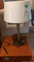 Photo of retro table lamp showing full lamp structure with white plastic shade and metal base on a wooden surface.