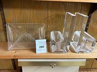 Clear acrylic retro desk items including two rectangular bookends, an open rectangular mail holder, and an envelope-shaped organizer, displayed on a wooden shelf.