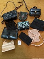 Nine small purses and handbags displayed on a carpeted floor, showing various textures and straps.