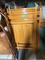 Four vintage wooden folding lawn chairs stacked together showing their foldable design and wood finish.