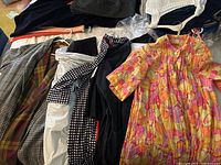 Overview of multiple women's dusters and robes including a floral patterned one and several black and muted colored ones.