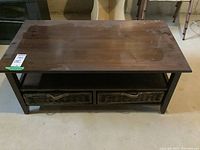 Full view of the wooden coffee table showing the top surface with scratches and scuffs, and the two wicker baskets beneath.