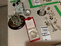 Multiple crystal figurines and keepsakes displayed on a white surface, including flowers, birds, and boxed item.