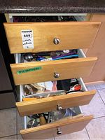Four kitchen drawers partially open showing assortment of cutlery and kitchen utensils inside
