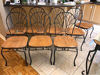 Set of eight wood and metal dining chairs arranged in two rows in kitchen area.
