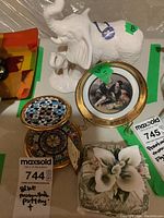 Photo showing white porcelain elephant figurine with Made in Canada tag, two Blue Mountain pottery items with detailed hand-painted patterns, porcelain floral figurine and decorative plate with classical painting and gold rim.