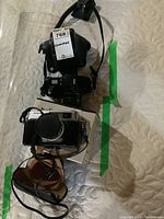 Full lot including Minolta cameras, cases, and sunglasses displayed on a quilted fabric.