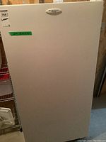Front view of white Frigidaire upright freezer with green label showing dimensions 28x28.5x59.5 inches