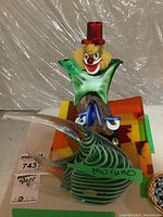Photo showing the full clown and fish figurines on a surface with sizing note and Murano label on fish.