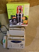 Brother IntelliFax fax machine with handset and Magic Bullet NutriBullet blender set in box, shown to identify fax machine and kitchen appliance.