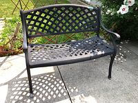 Front view of black lattice bench on concrete patio