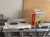 Photo of Salton HP1210 electric coil cooktop box and Sunbeam blender box together, showing lot contents.