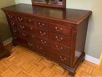 Photo of Thomasville wooden dresser with nine drawers and brass handles, showing the polished wood finish and detailed brass hardware.
