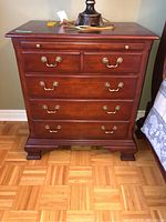 Front view of Thomasville nightstand showing all drawers with brass handles and pull-out platform below the top drawer.
