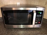 Full view of Toshiba microwave on countertop showing stainless steel exterior and door with handle.