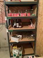Full view of utility shelf in basement showing four particle board shelves within black metal frame. Shelf has items stored but contents not included.