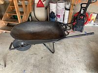 Full side view of the wheelbarrow showing tub, wheel, and handles