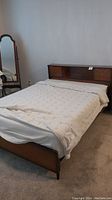 Full view of double bed frame with bedding covering the mattress area showing the wood construction and overall shape.