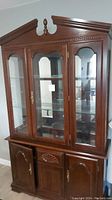 Front view of the two-piece china cabinet showing wood construction with cherry finish, glass doors on upper section and wooden doors on lower section