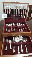 Full cutlery set in the open wooden box showing all the utensils organized in slots within a burgundy velvet lining.