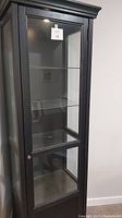 View of the full height espresso colored IKEA display cabinet showing glass front and wooden frame.