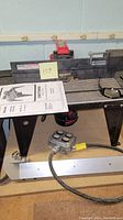 Craftsman router table with fence, instruction manual on top, and power cord with control switch visible.