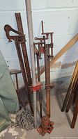 Photo showing hydraulic bottle jack, two farm jacks, metal chain, and metal poles stored in basement corner