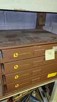 Four brown metal storage cabinets from Lawson Products stacked with multiple drawers. Cabinets show wear and dust. Photo taken to show overall lot contents and condition.