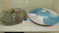 Photo showing both lazy Susan trays, one clear glass with metal holder and one blue and white ceramic segmented tray.