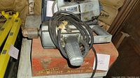 View of Milwaukee right angle drill on orange metal carrying case with attached power cord, labeled 'Right Angle'.