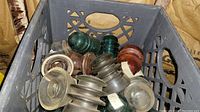 Crate filled with assorted vintage glass insulators showing various colors and shapes.