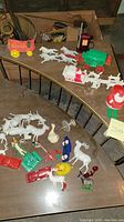 Overview of the vintage plastic figurines and toys spread out on tables including multiple Santas, reindeer, wagons, and various animal figurines.