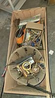 Wood box filled with assorted plumbing and hardware parts with broom handle on side