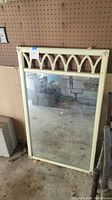 Full view of the vintage wood framed mirror with gothic arch pattern at top in a storage setting.