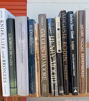 Front view of 11 sculpture books lined up, titles visible including Rodin, Gauguin, Henry Moore, and European bronzes