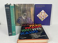 Five art books on a white surface, titles visible: Magritte, Rivers, Bacon, Mondrian, Picasso.