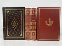 Front view of all four leather bound books together showing covers and spine designs.